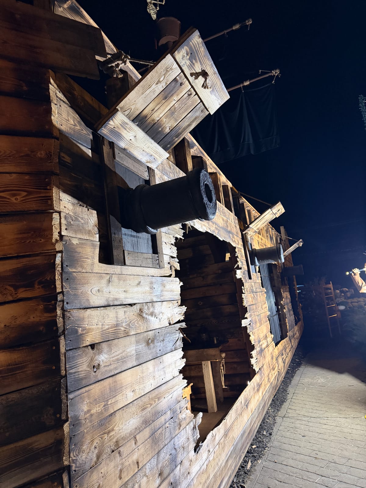 Cannons and splintered planks along the side of the pirate ship at night